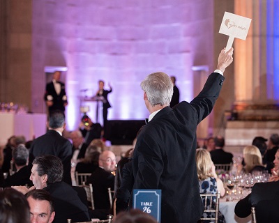 Man standing holding up bidder paddle